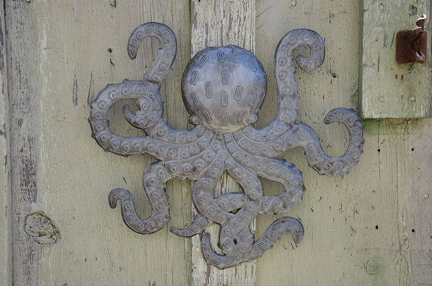 Handmade Haitian hammered metal wall art of an octopus hanging outside