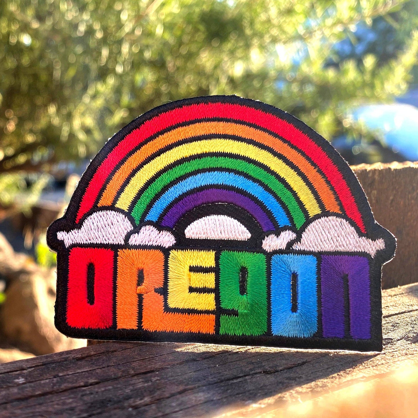 Rainbow-colored patch with 'Oregon' text on a wooden surface outdoors