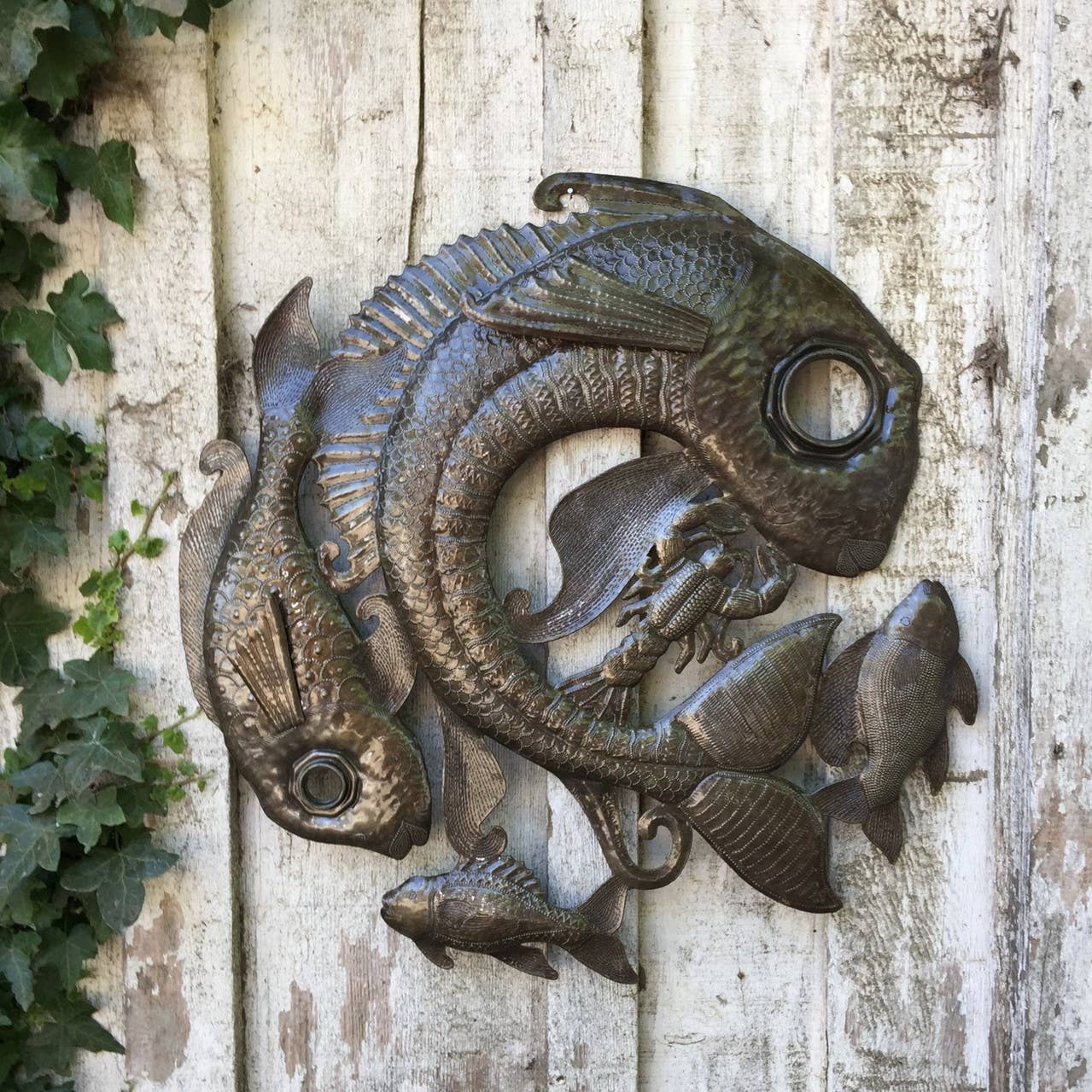Handmade Haitian hammered metal wall art of fish and sea life hanging outside