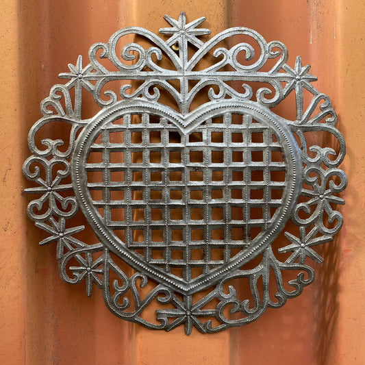 Handmade Haitian hammered metal wall art of a heart hanging inside.