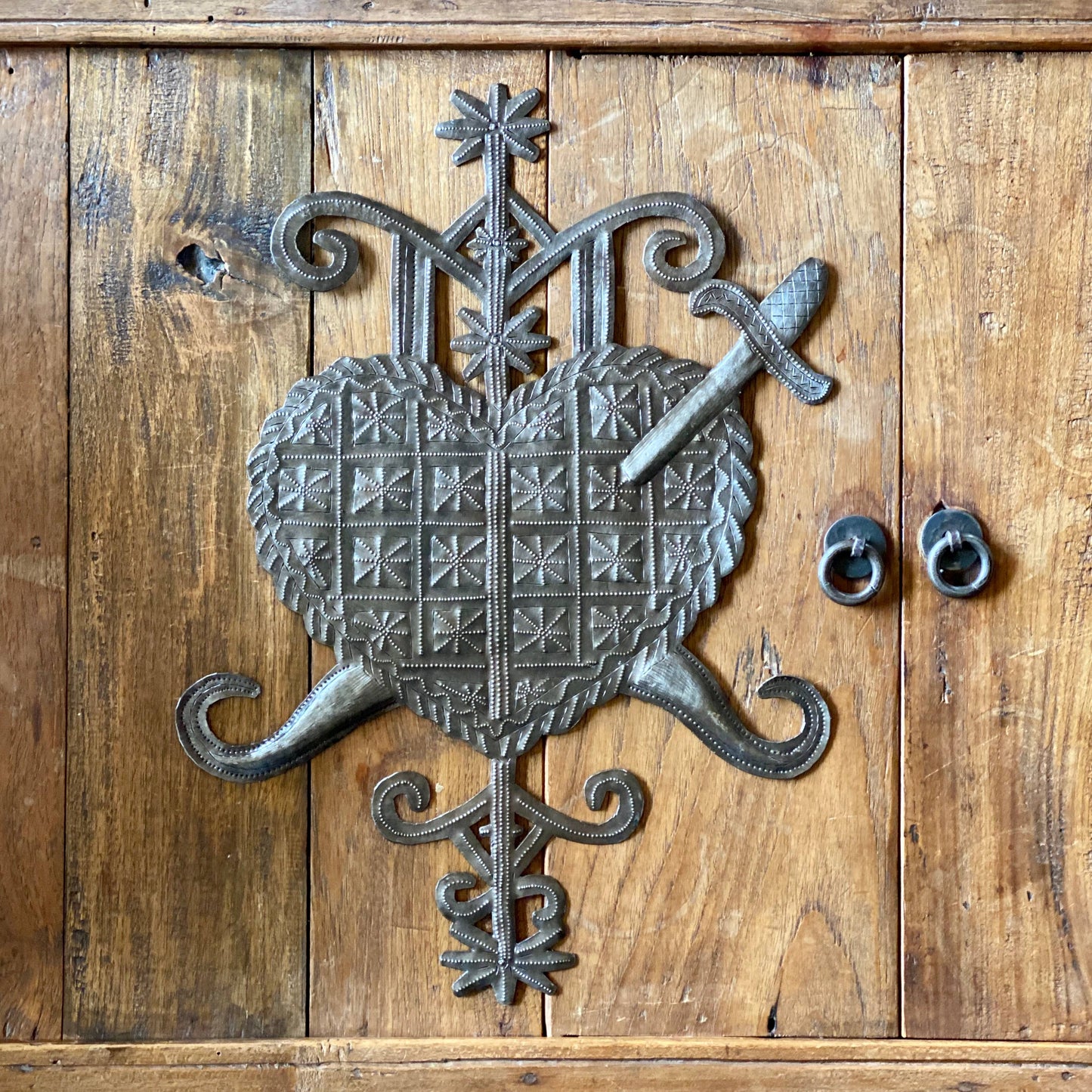 Handmade Haitian hammered metal wall art of a heart with a sword through it