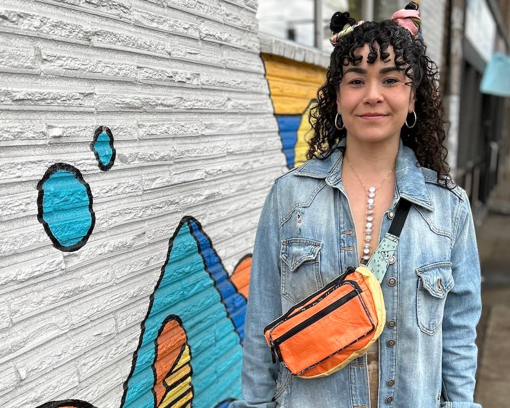 Person wearing the cross body pack. Exterior material is upcycled from feed and cement bags, Interior material is recycled from plastic bottles. Each design is unique.