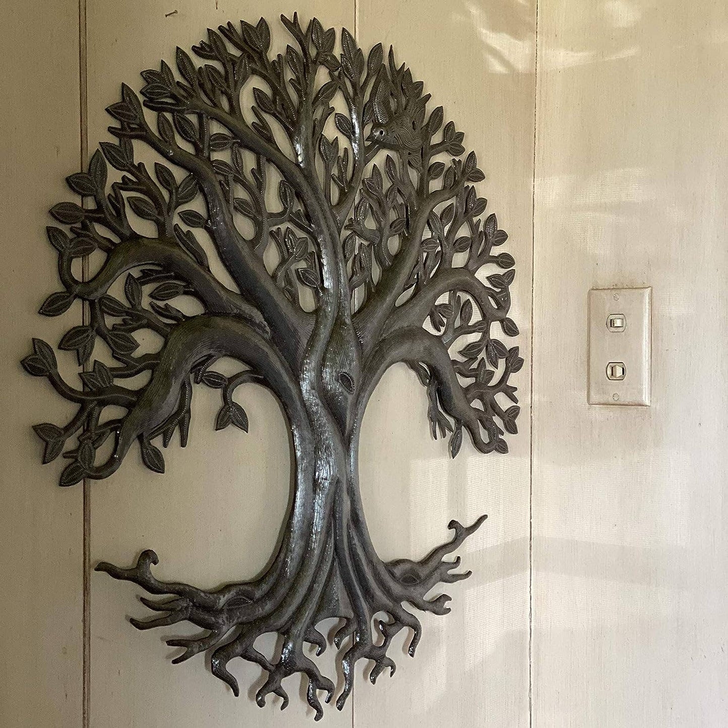 Handmade hammered metal wall art of a tree of life hanging inside