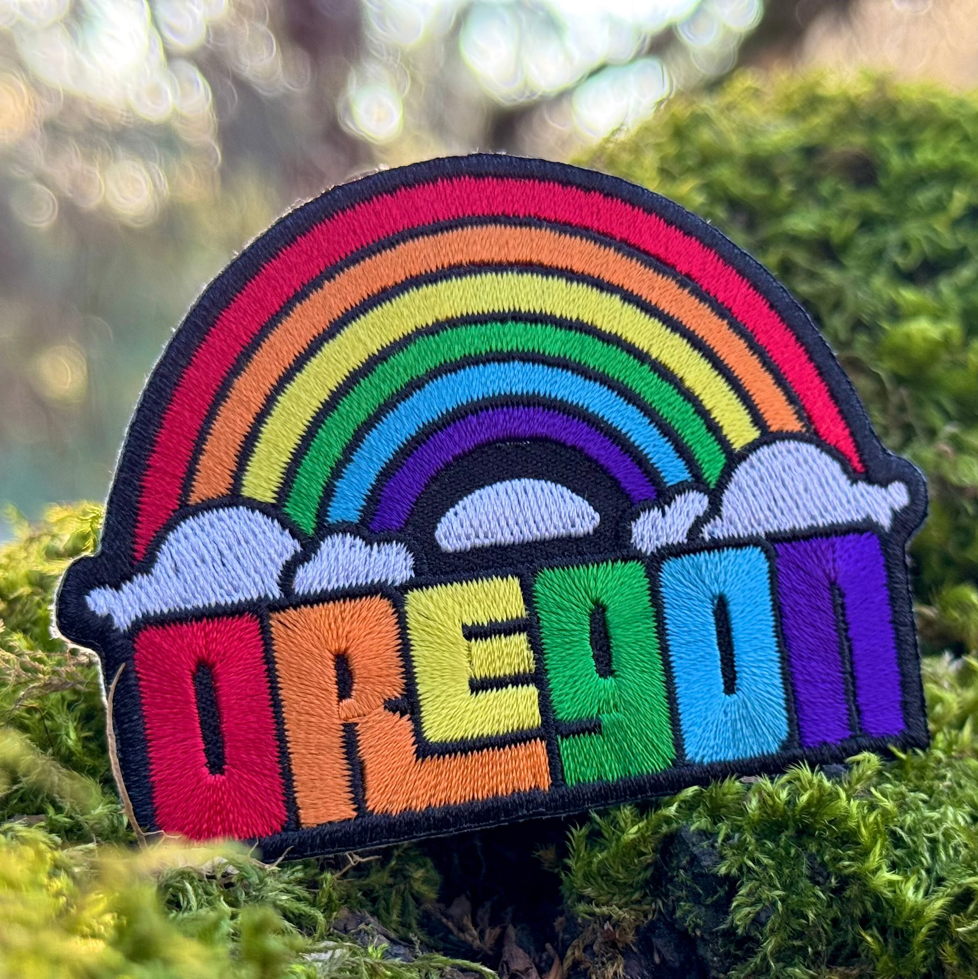 Colorful rainbow patch with 'Oregon' text on a green moss background