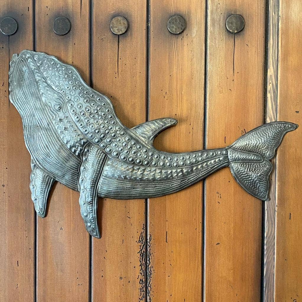 Handmade Haitian hammered metal wall art of a whale hanging outside