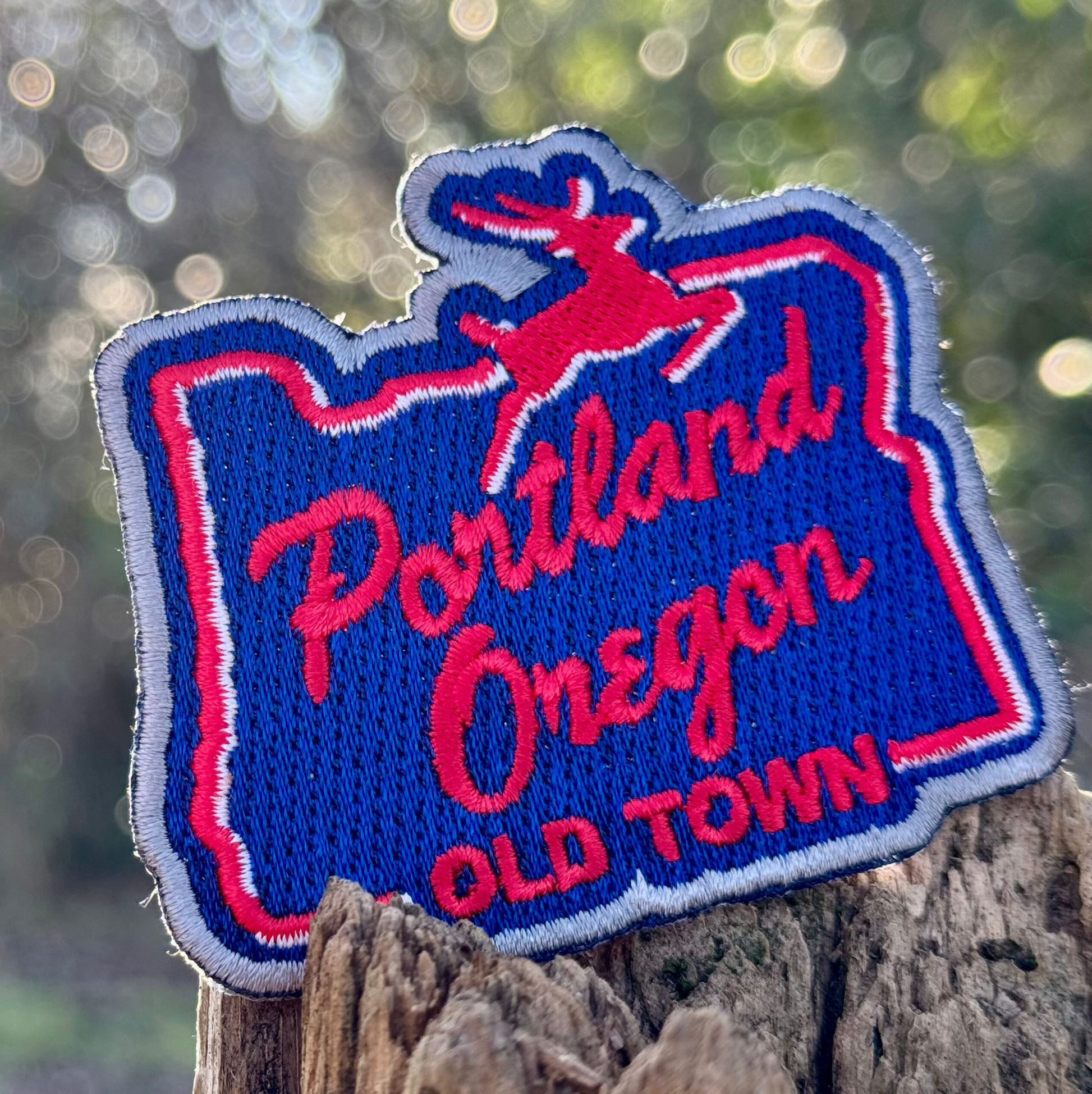 Embroidered patch of Portland, Oregon with a deer design on a wooden post.