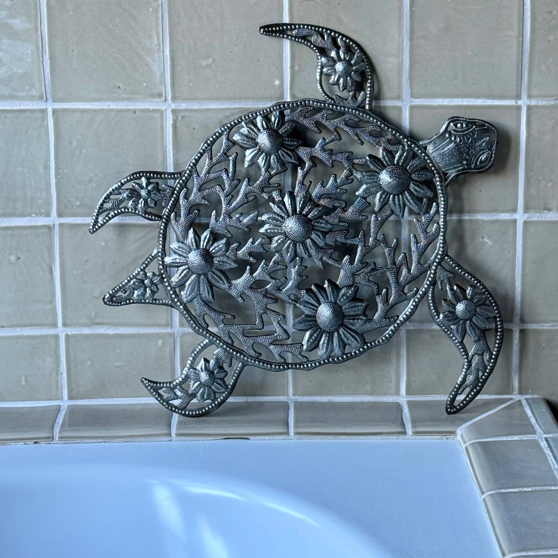 Handmade hammered metal wall art of a turtle with flowers on tile