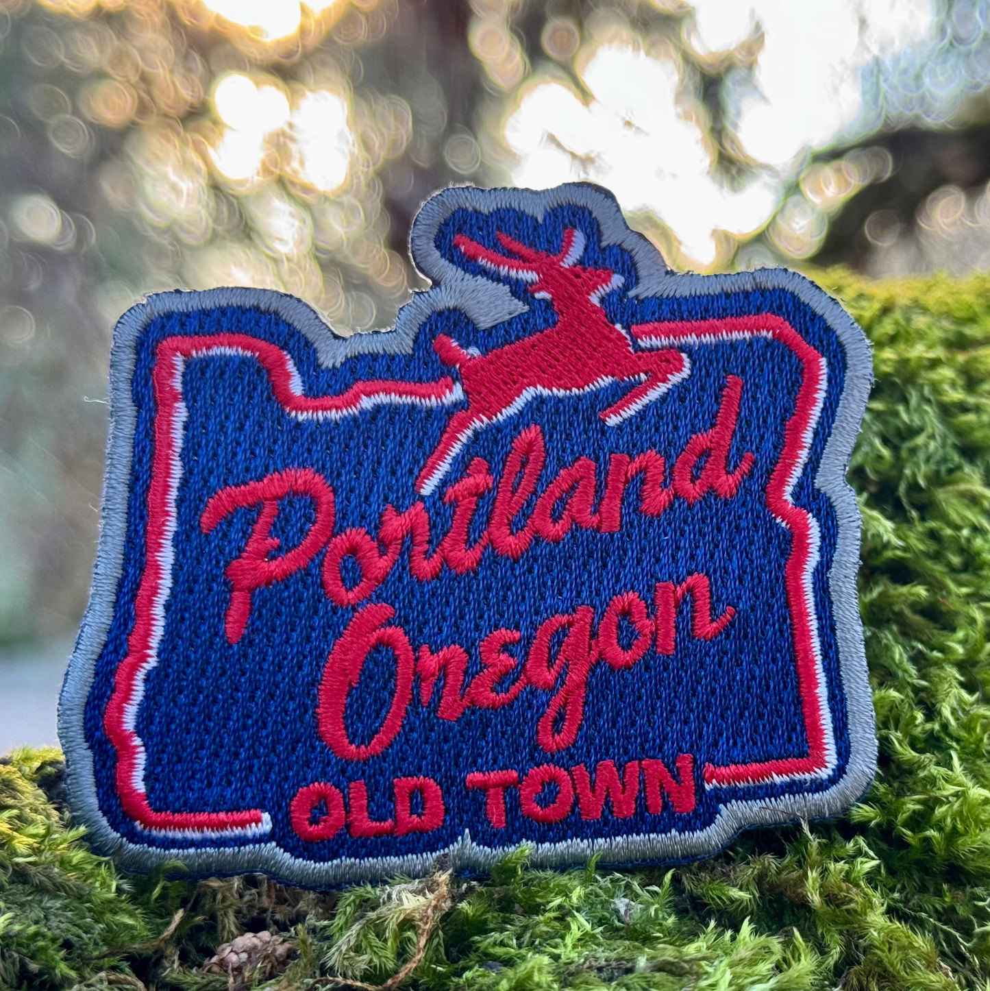 Embroidered patch of Portland, Oregon with a deer design on green moss.