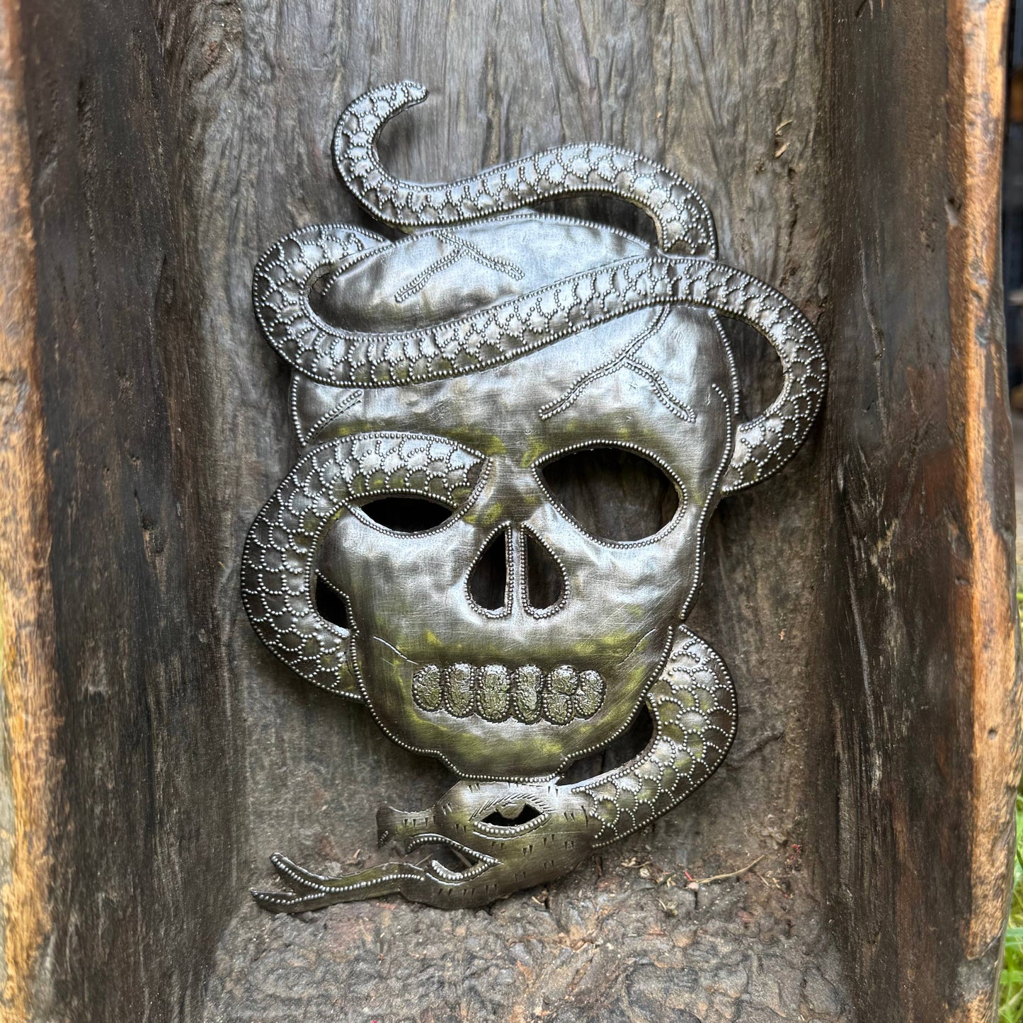 Handmade Haitian hammered metal wall art of a skull with a snake entwined
