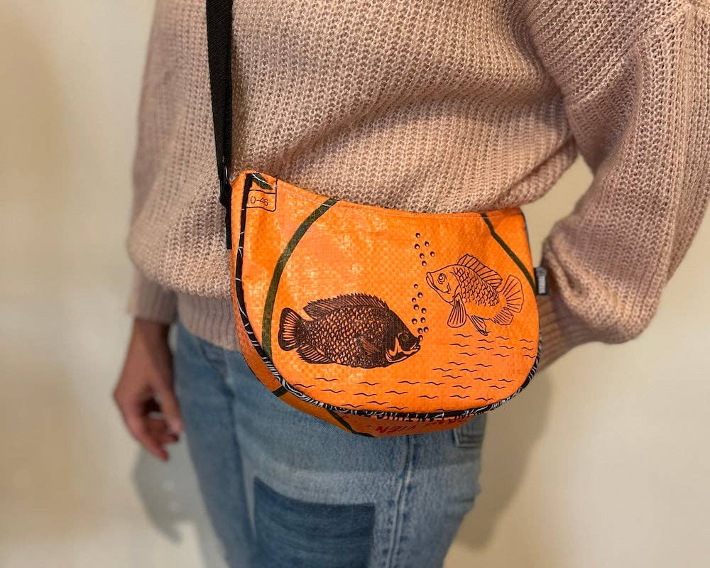 Person wearing cross body style bag. Exterior material is upcycled from feed and cement bags, Interior material is recycled from plastic bottles. Each design is unique.