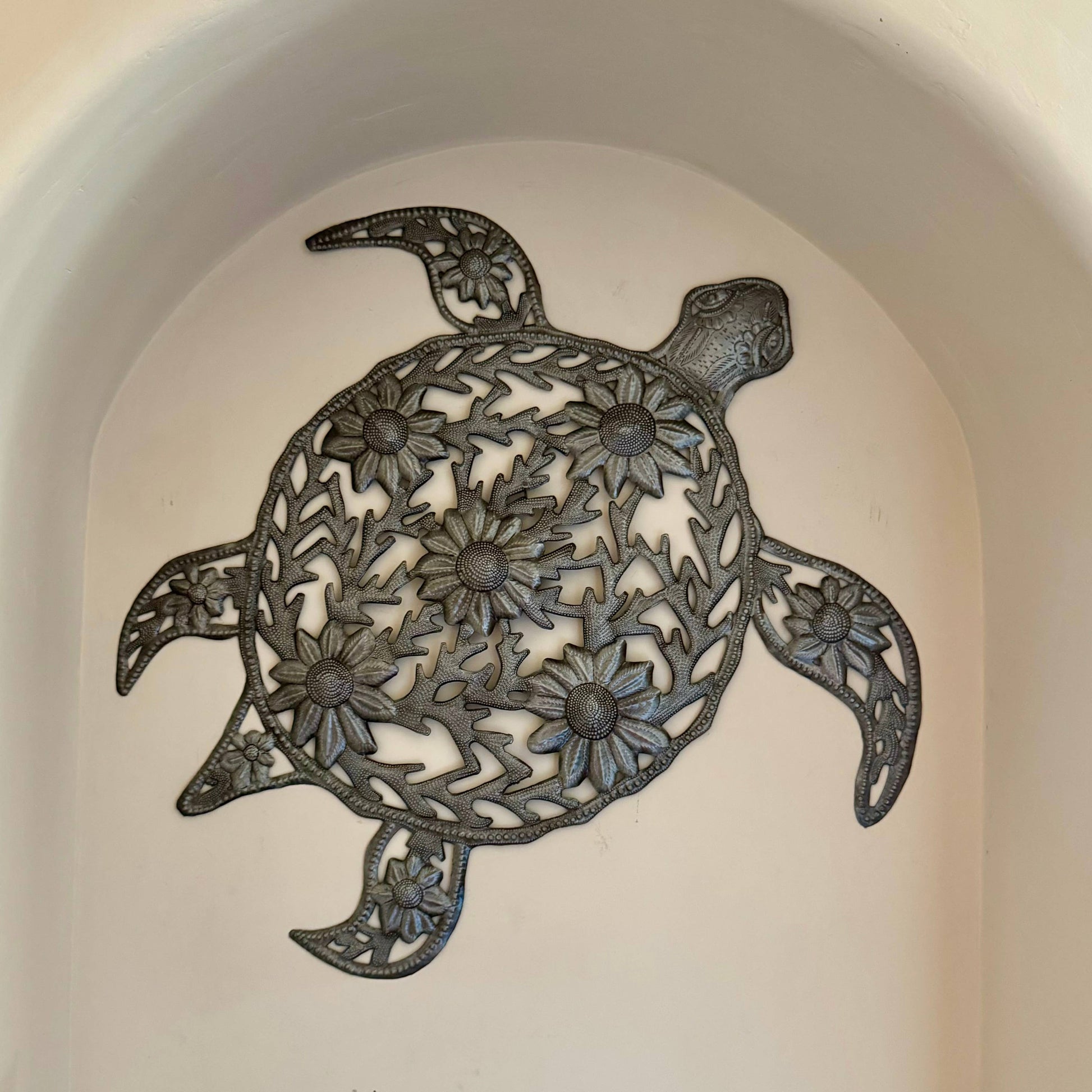Handmade hammered metal wall art of a turtle with flowers.