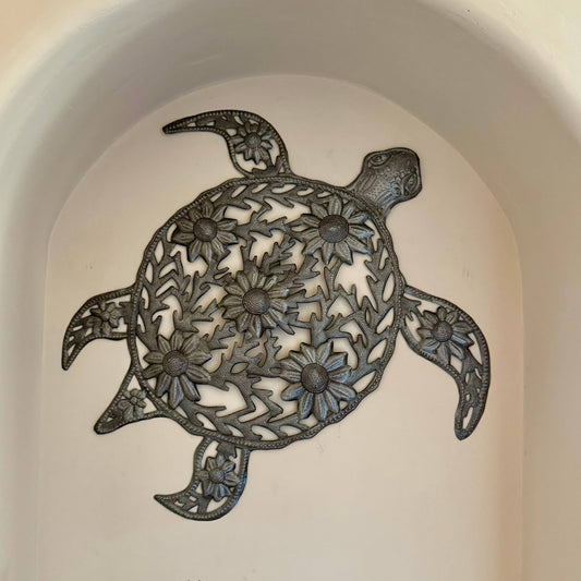 Handmade hammered metal wall art of a turtle with flowers.