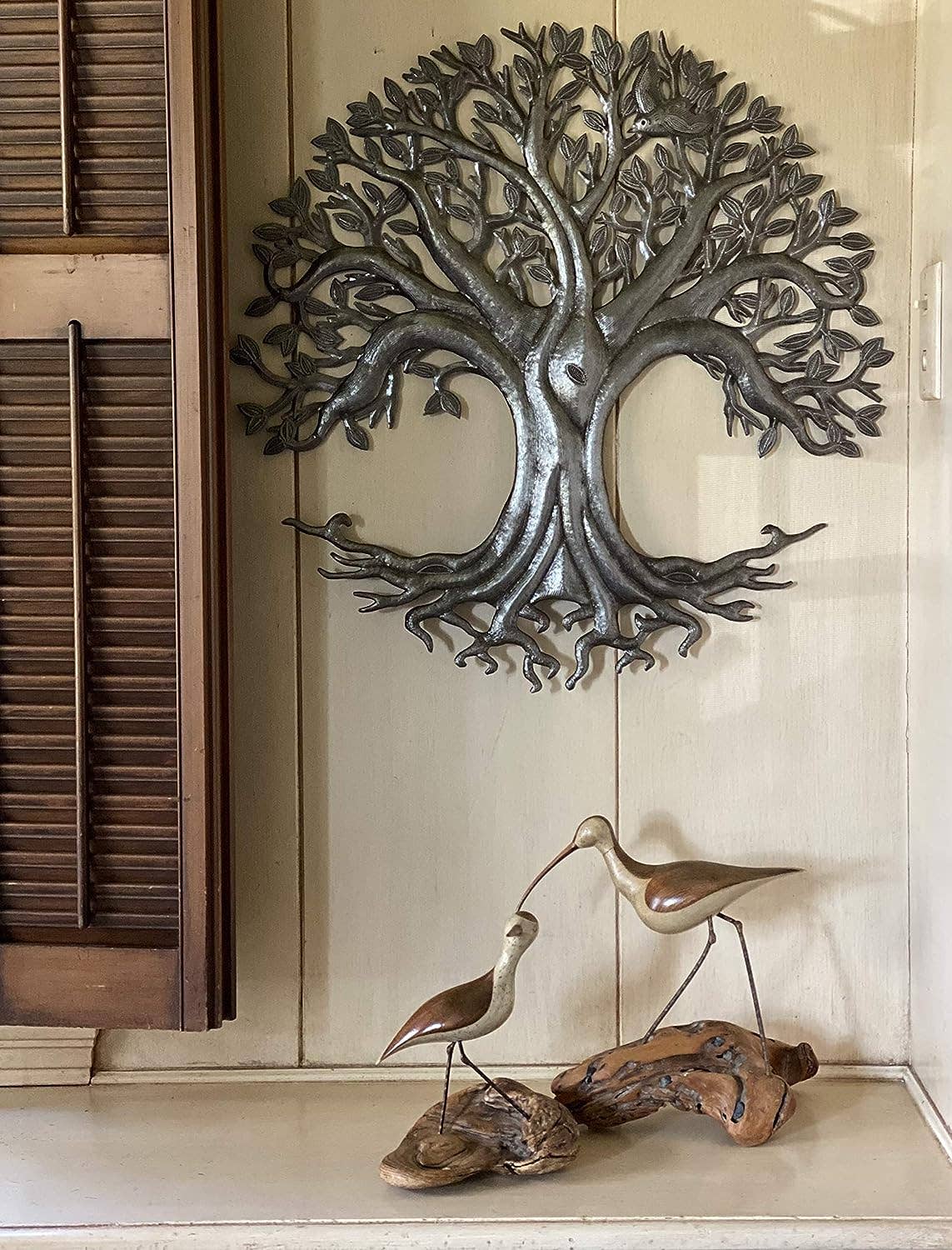 Handmade hammered metal wall art of a tree of life hanging inside