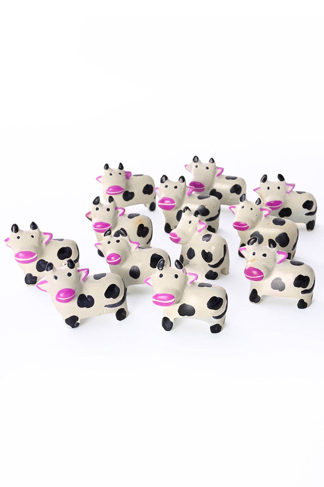 A dozen handcrafted soapstone cows with pink snouts and ears. 