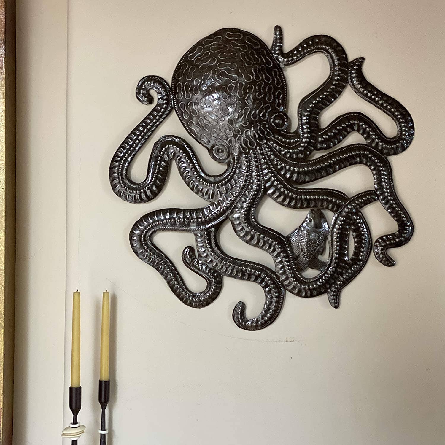 Handmade Haitian hammered metal wall art of an octopus and fish hanging inside