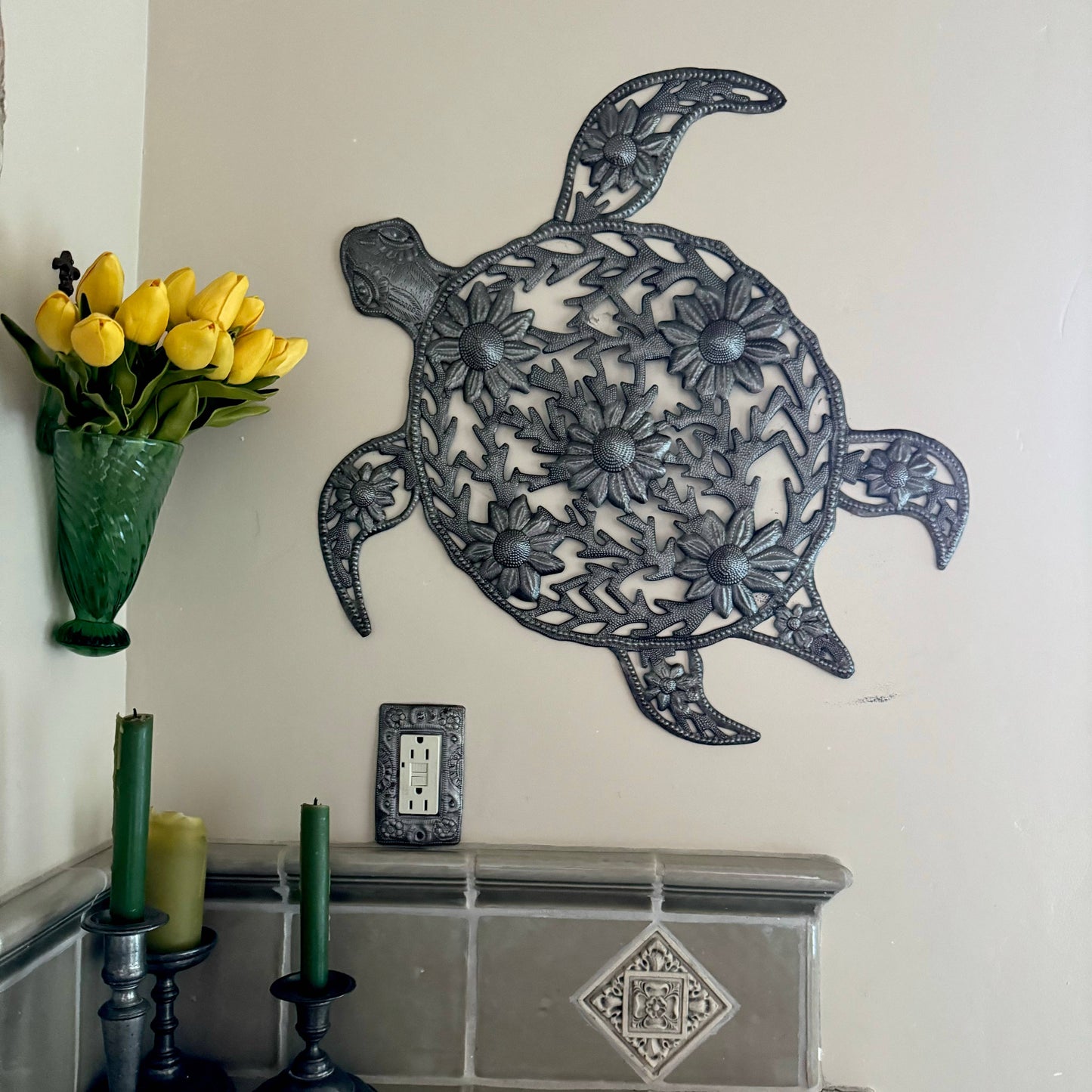 Handmade hammered metal wall art of a turtle with flowers hanging inside