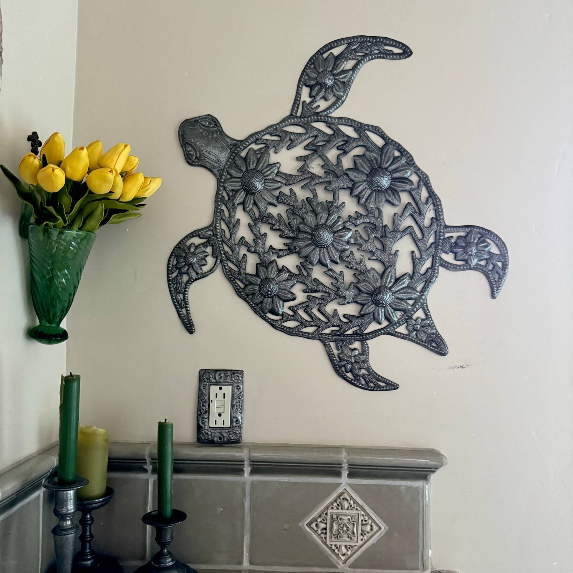 Handmade hammered metal wall art of a turtle with flowers hanging inside