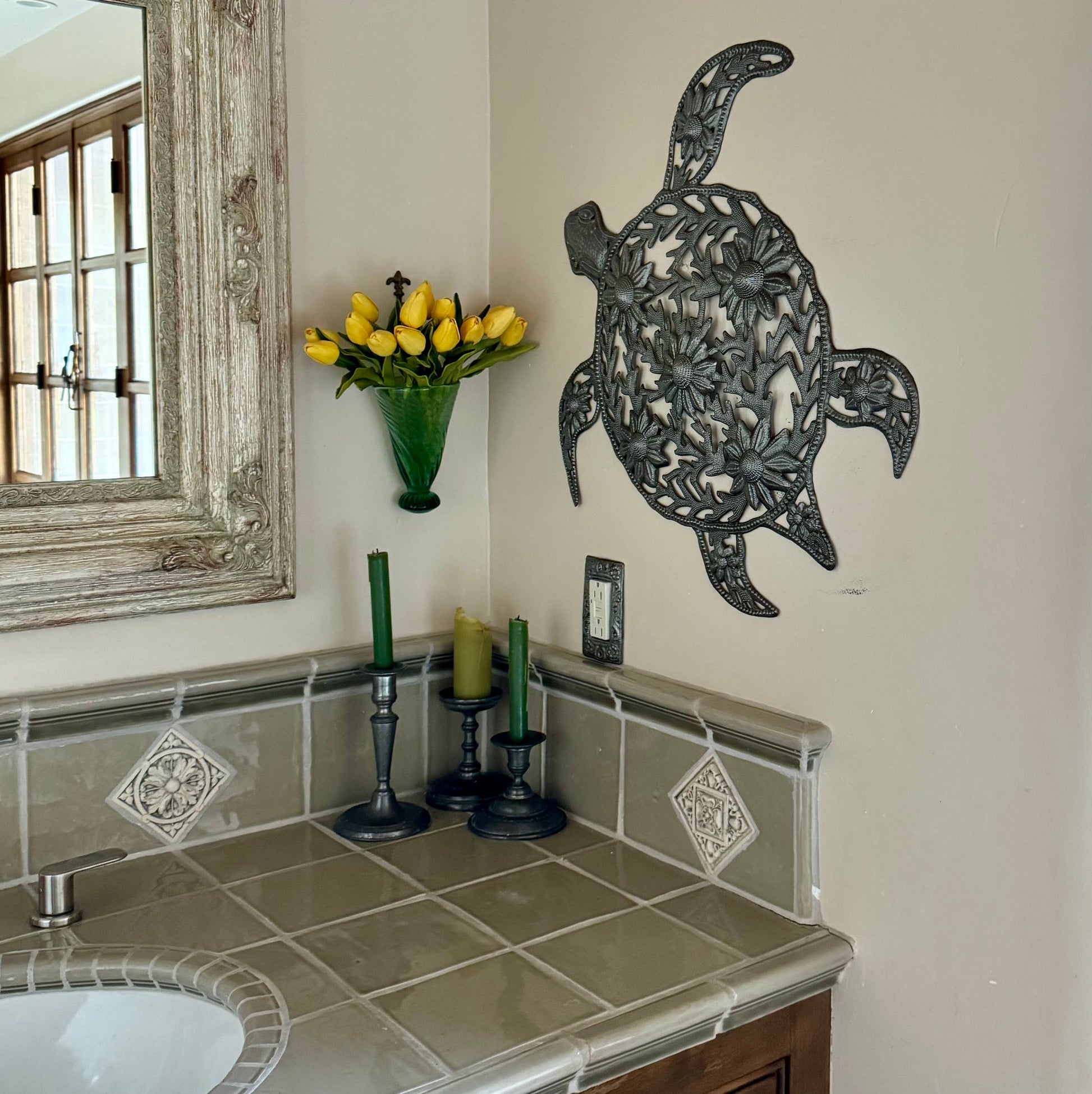Handmade hammered metal wall art of a turtle with flowers hanging inside