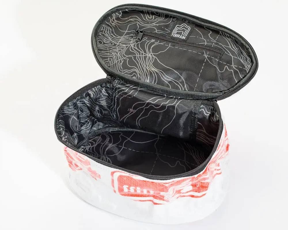 Open oval travel pouch showing a spacious interior and zipper pocket in the top. Exterior material is upcycled from feed and cement bags, Interior material is recycled from plastic bottles. Each design is unique.