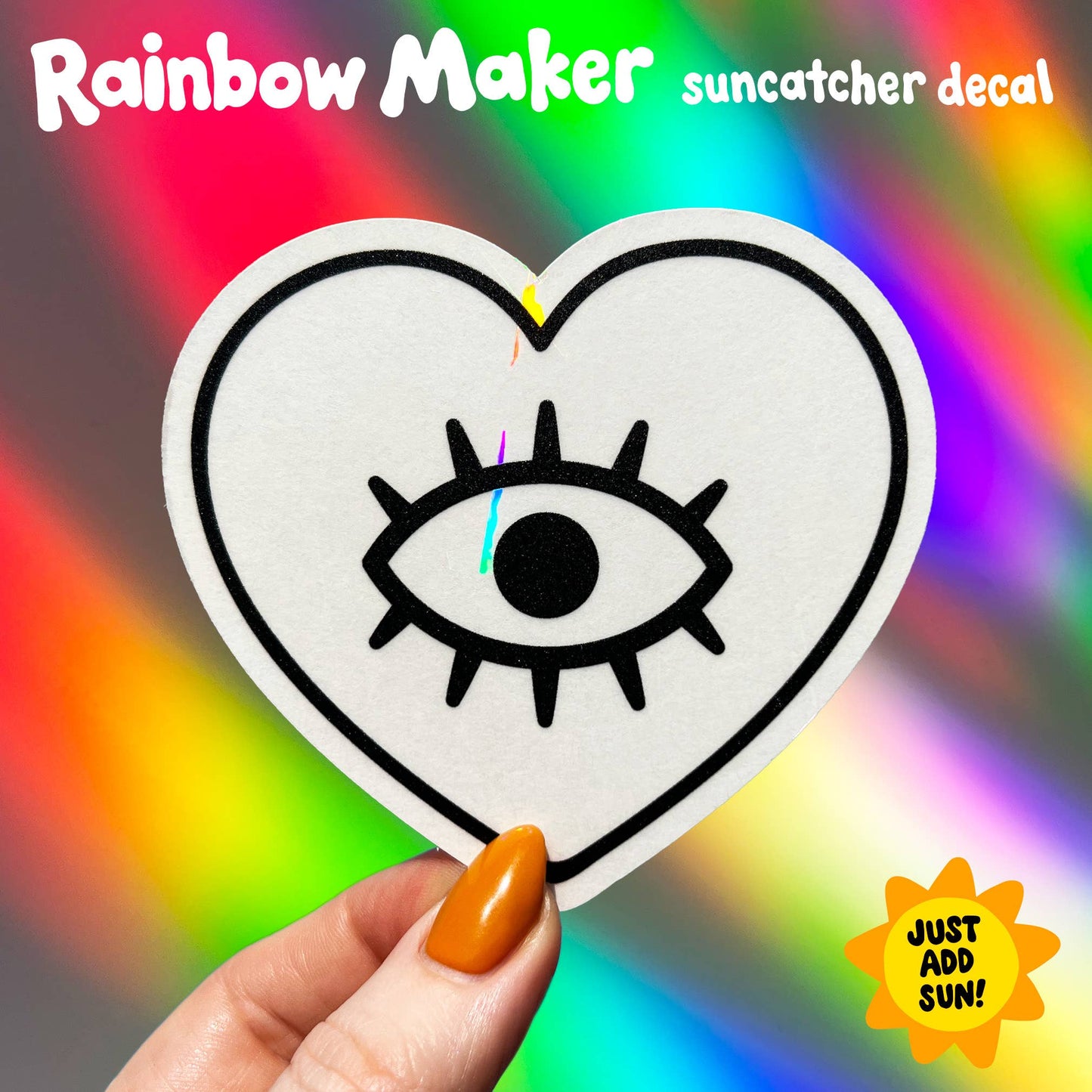 Heart-shaped suncatcher decal with an eye design held by a hand against a colorful background.