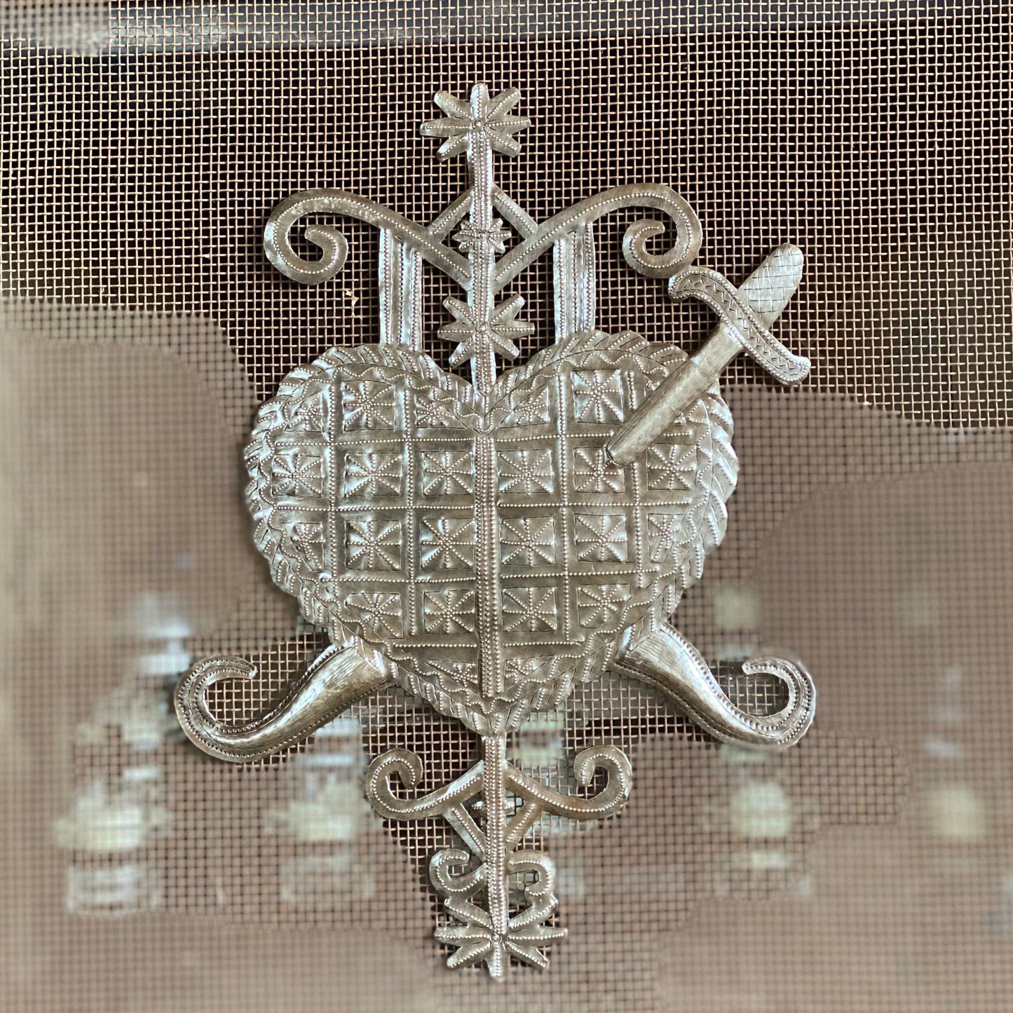 Handmade Haitian hammered metal wall art of a heart with a sword through it