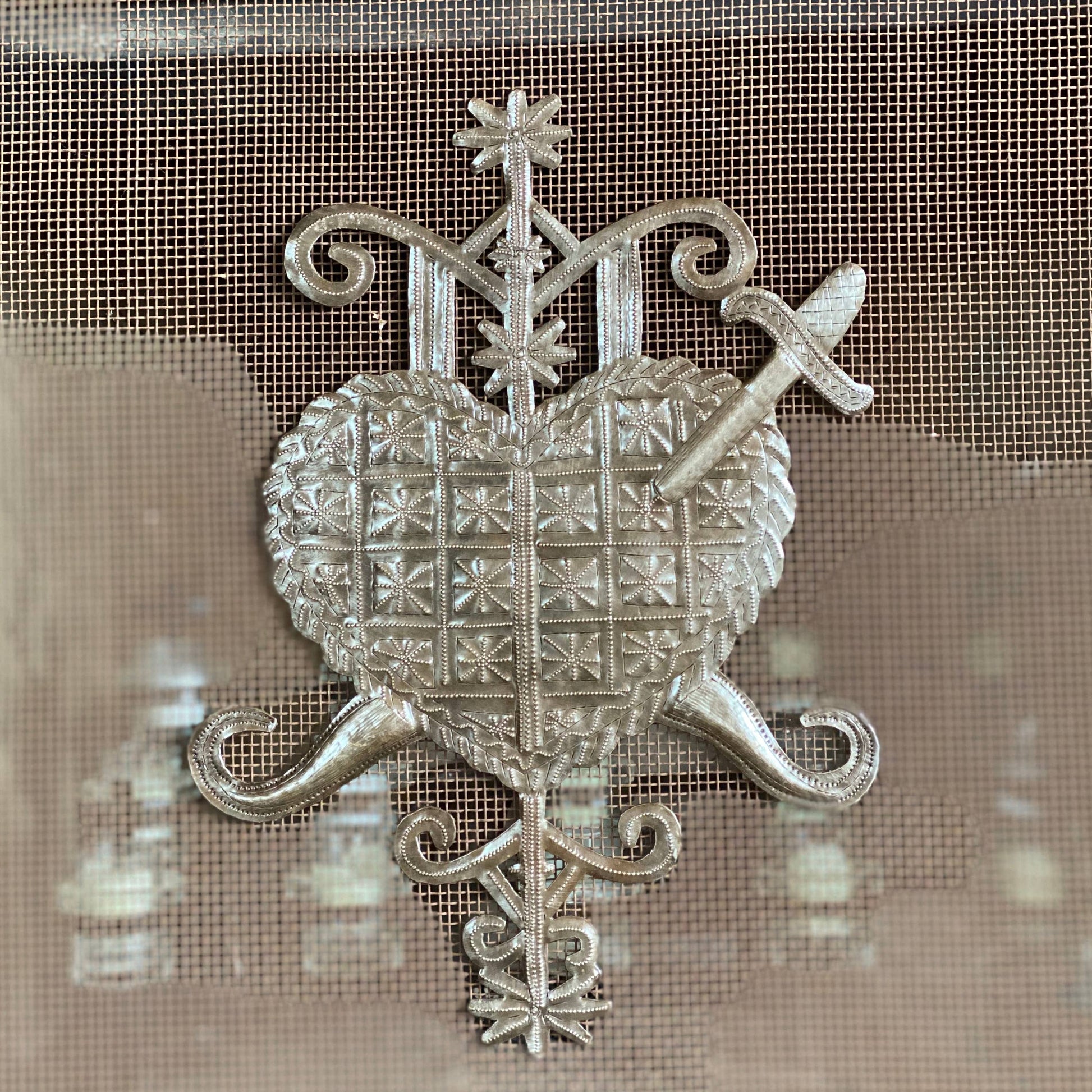 Handmade Haitian hammered metal wall art of a heart with a sword through it