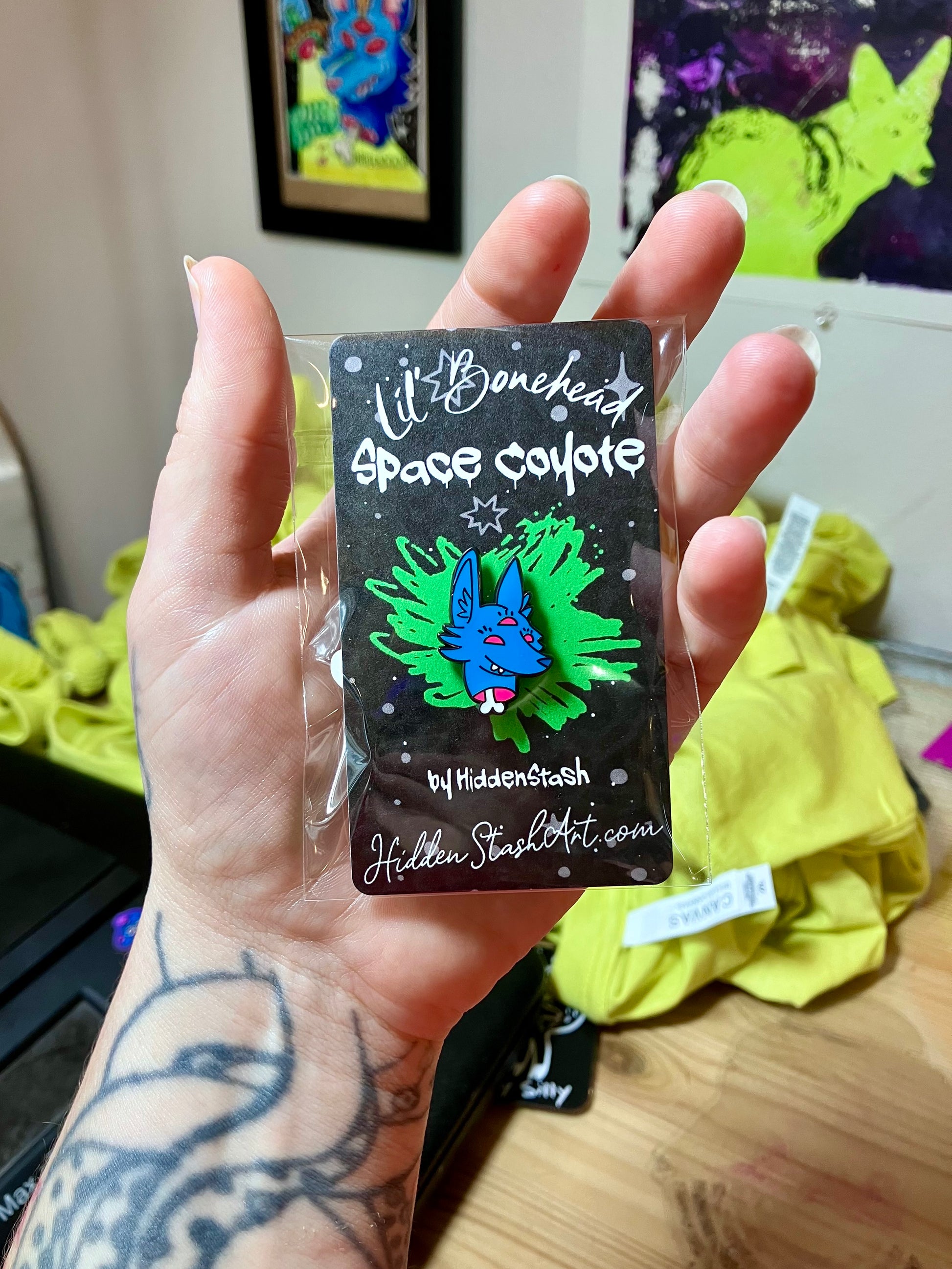 Handing holding the Enamel pin with cartoon character Space Coyote by HiddenStash in packaging