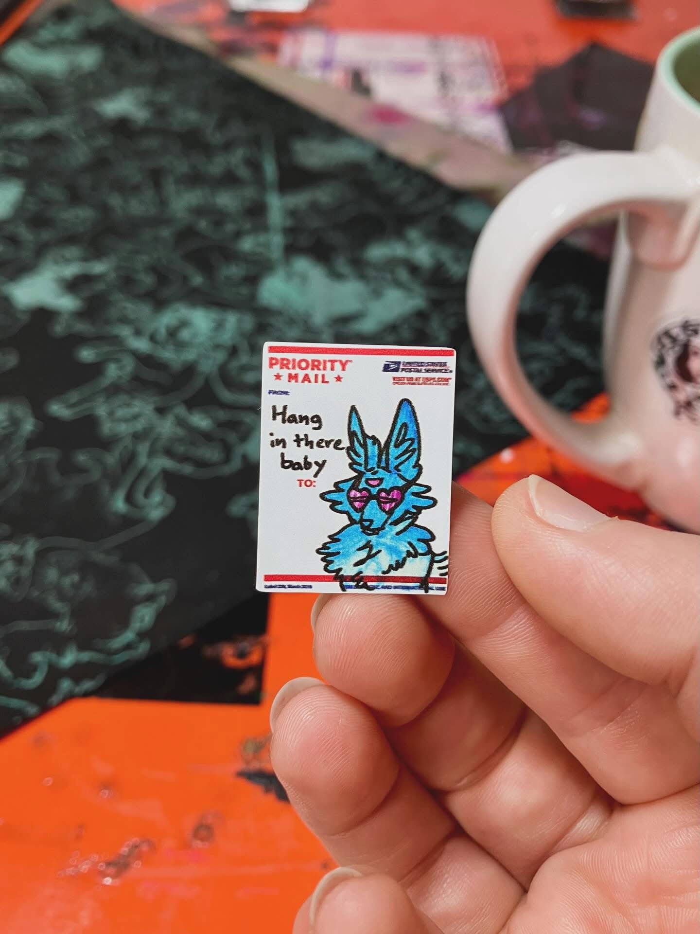 Ticker of a three eyed blue coyote that reads "Hang in there baby"