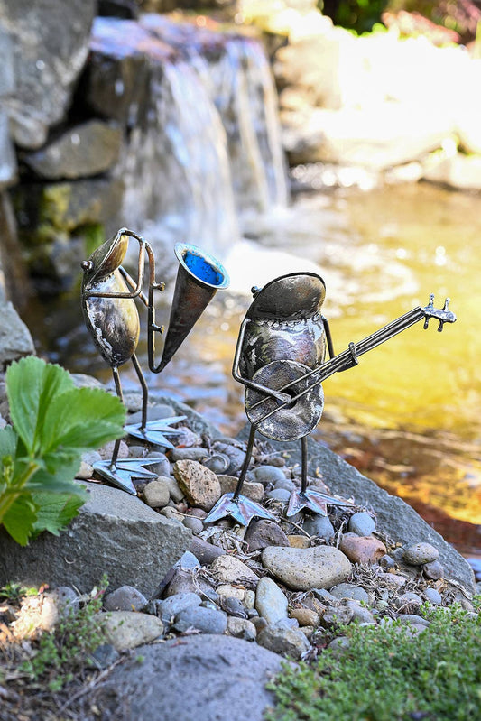 Two metallic frogs standing by the river, one playing the horn, the other a banjo.
