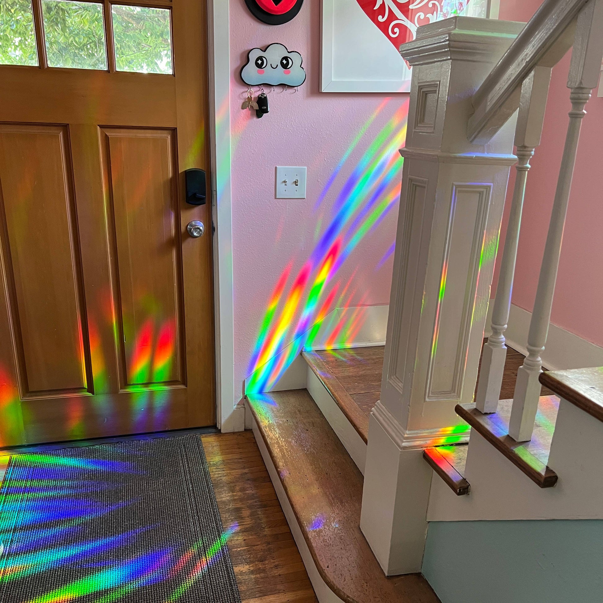 Rainbow light projection on a wooden door and staircase inside a house by the suncatcher decal.