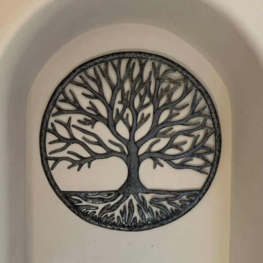 Handmade Haitian hammered metal wall art of a tree hanging in an alcove