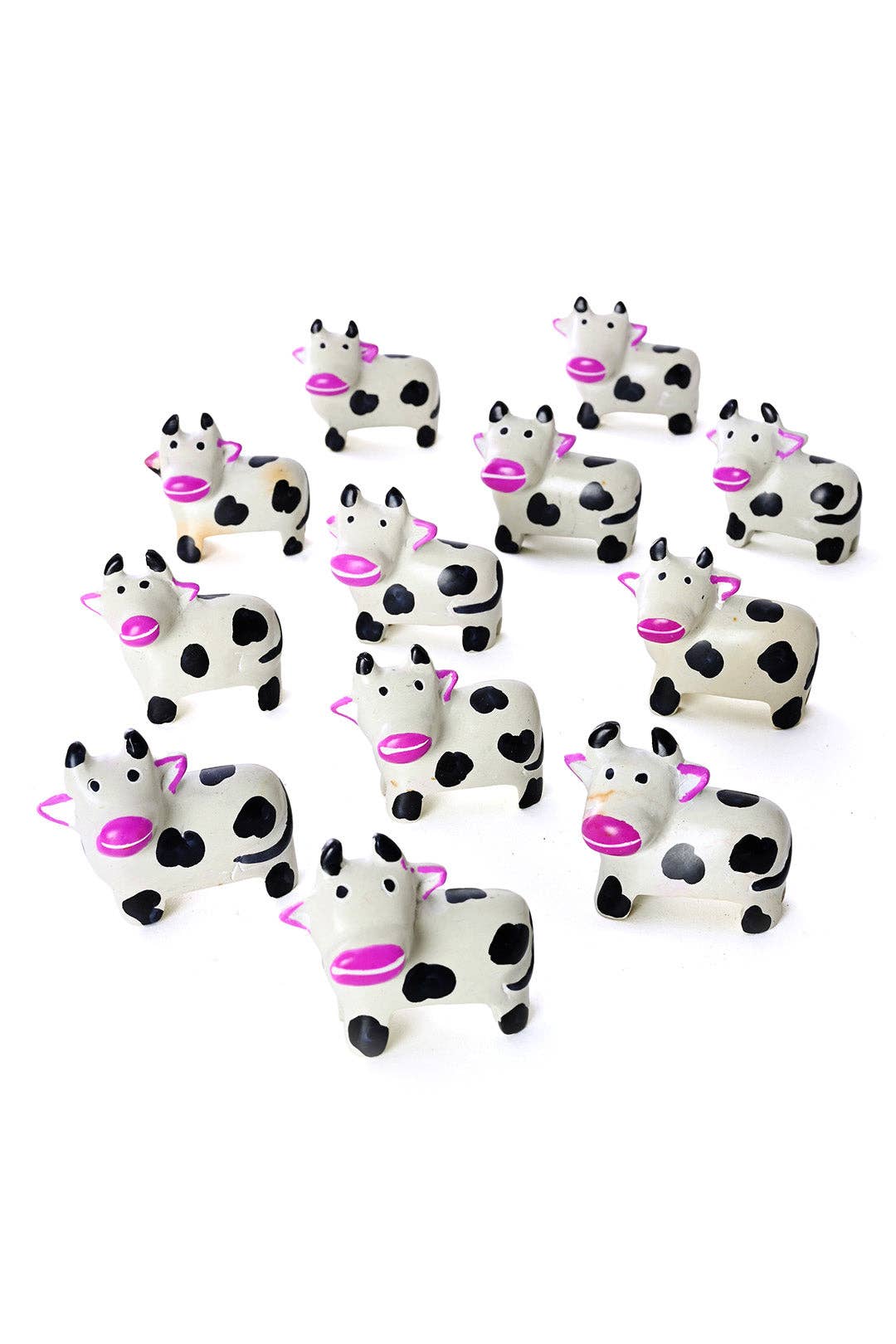 A dozen handcrafted soapstone cows with pink snouts and ears. 