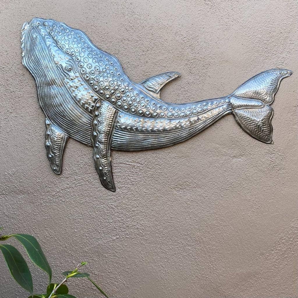 Handmade Haitian hammered metal wall art of a whale hanging outside