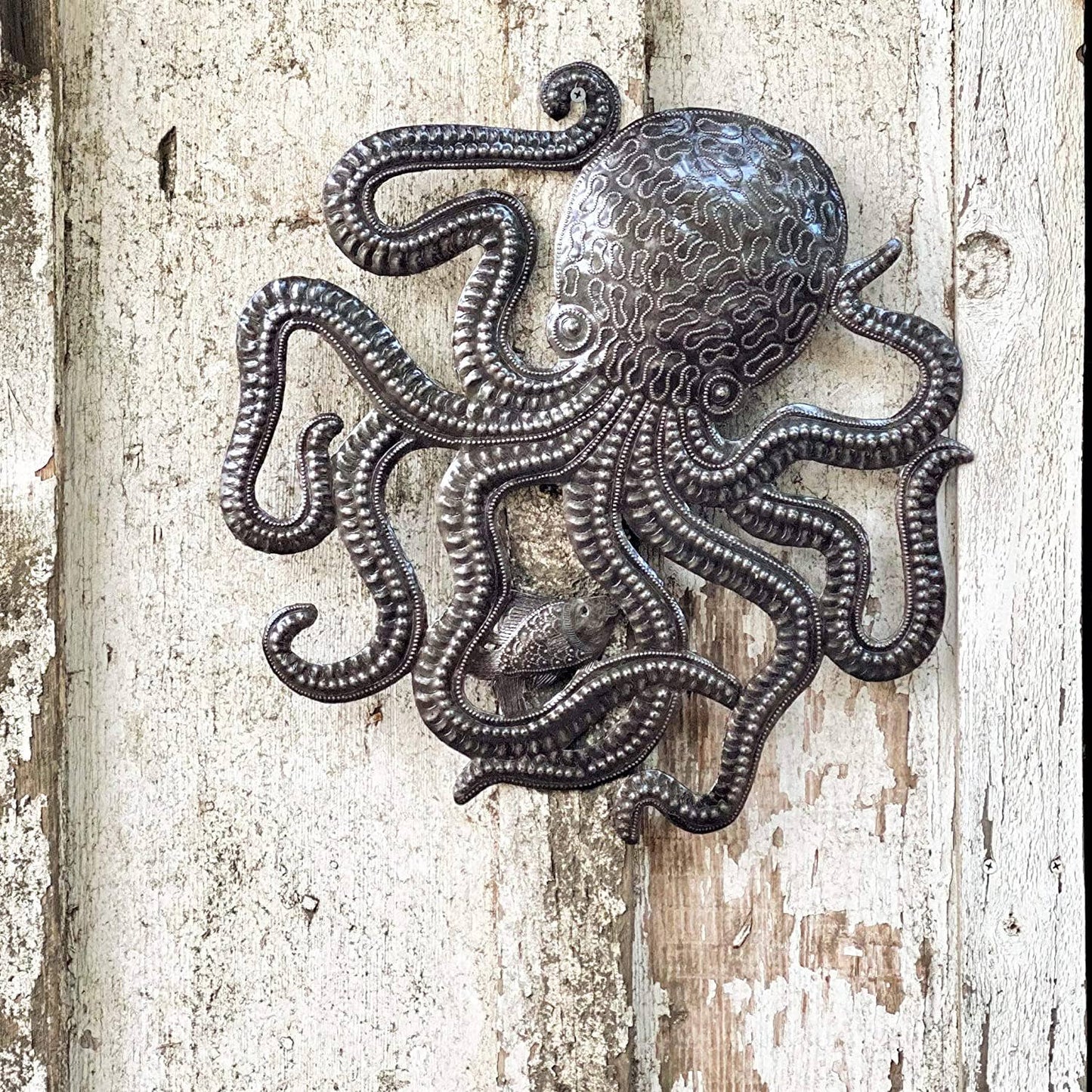 Handmade Haitian hammered metal wall art of an octopus and fish hanging outside