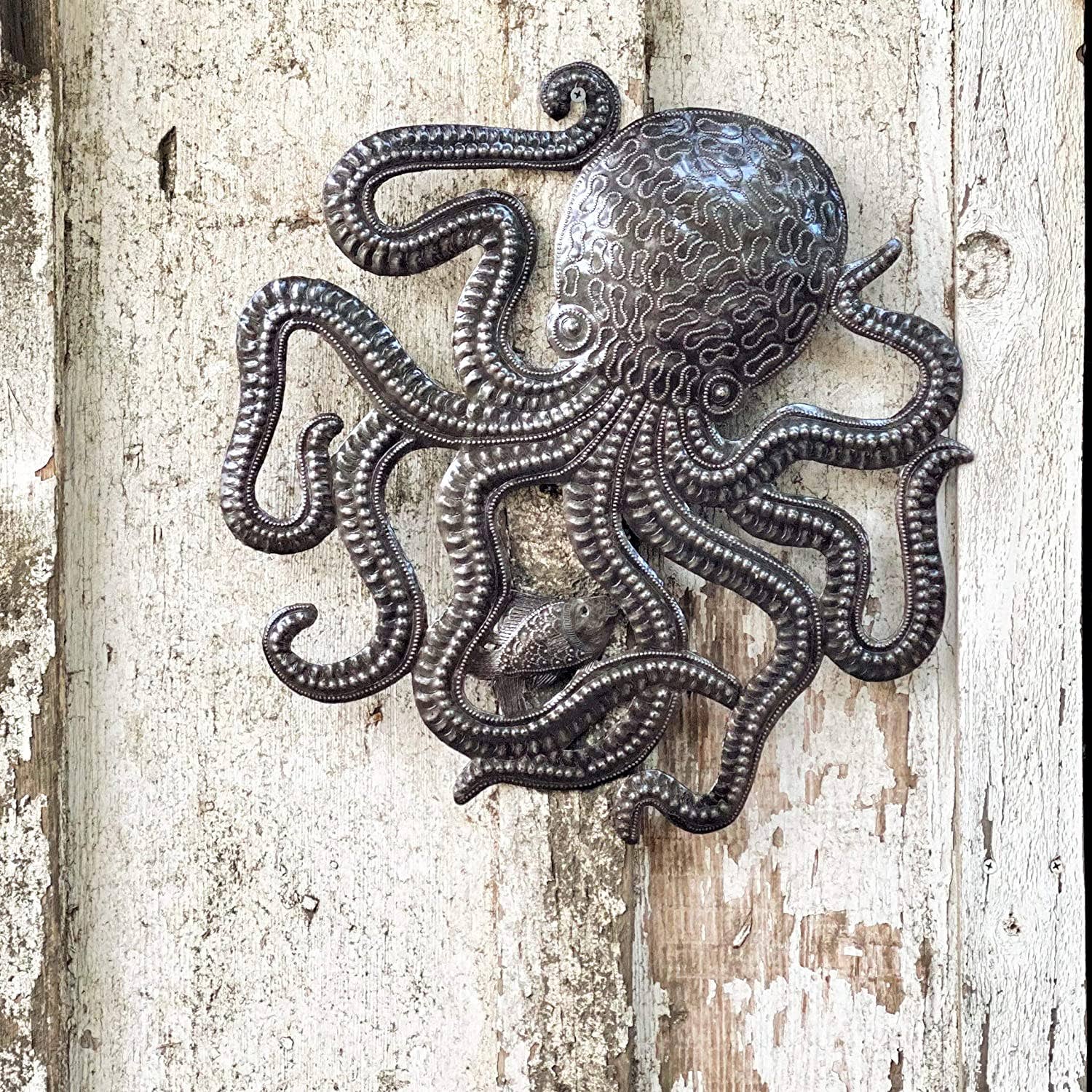 Handmade Haitian hammered metal wall art of an octopus and fish hanging outside