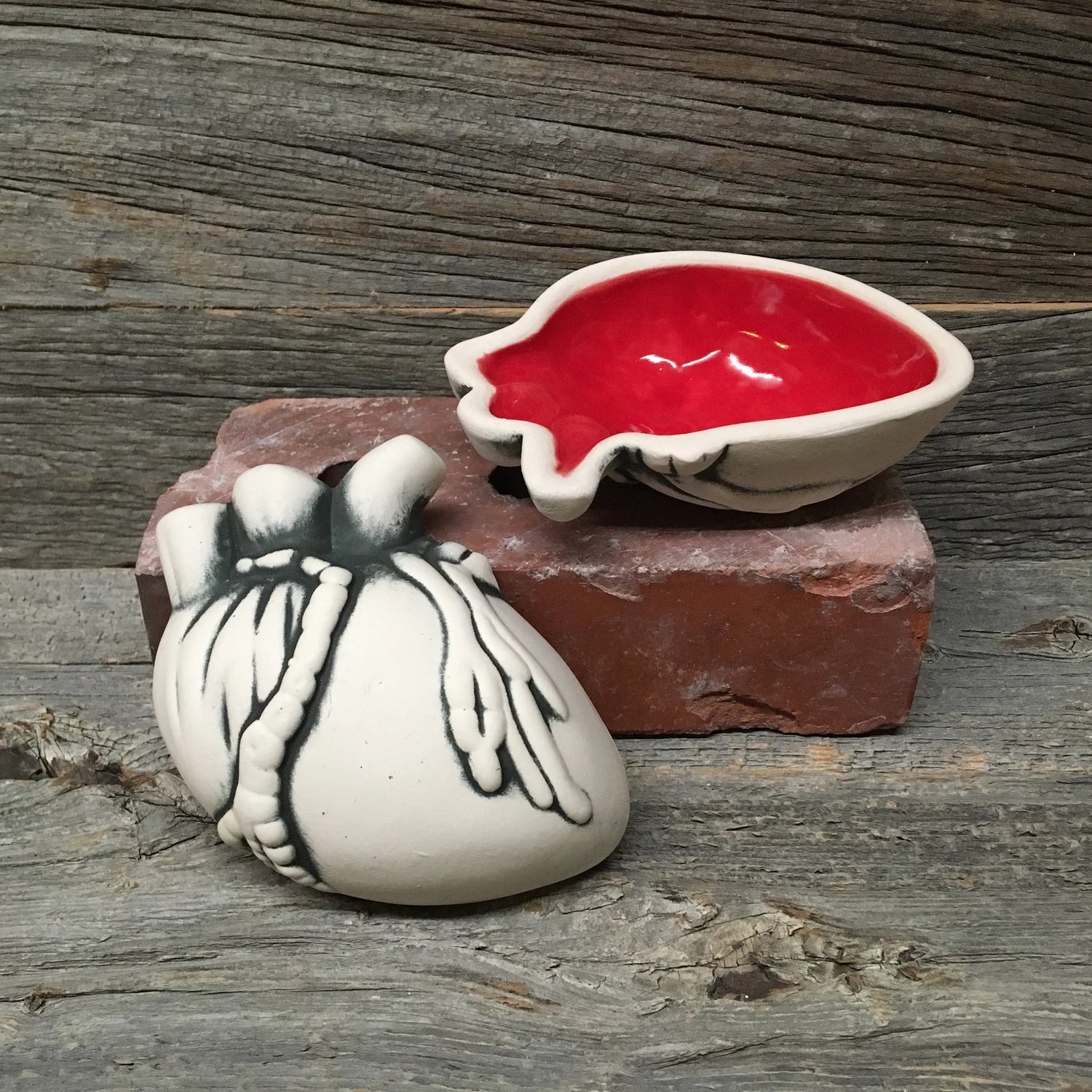 Ceramic bowl of an anatomical heart, opened to show the red interior.